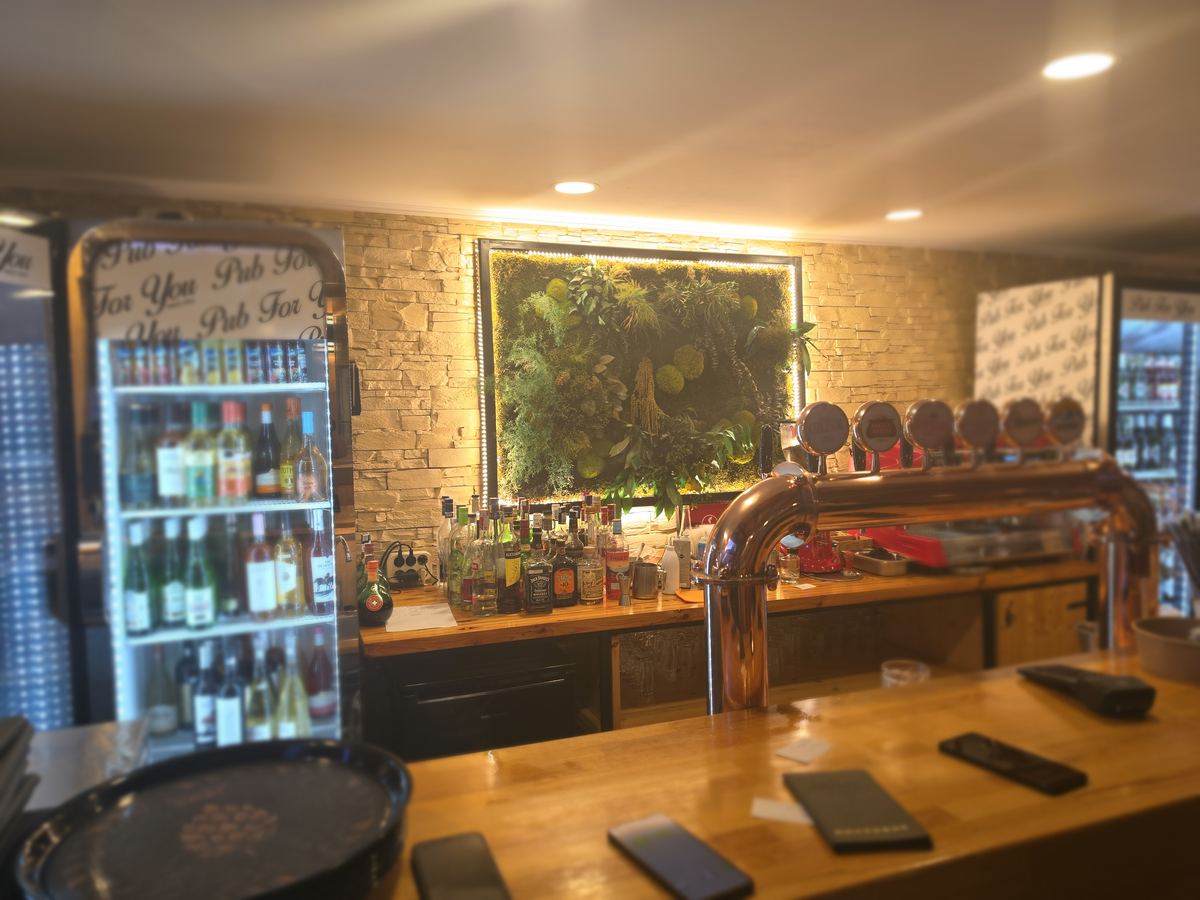 Barul restaurantului Pub For You, cu robinete de bere și perete vegetal